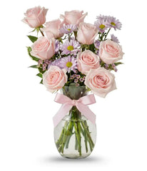 Pink bouquet of roses, daisies, waxflower, carnations and pittosporum in a vase with a pink bow on it