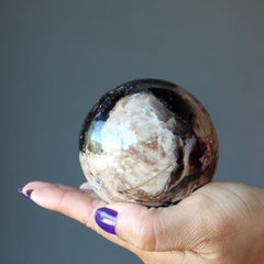 hand holding brown opal sphere