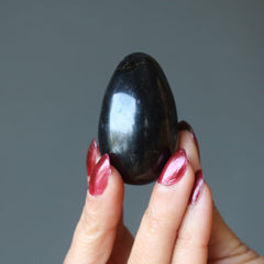 hand holding up a black tourmaline egg