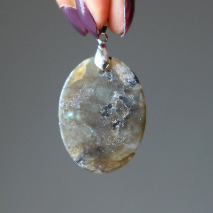 hand holding oval labradorite pendant showing flat back