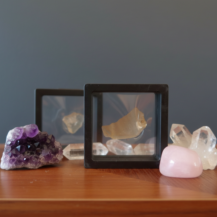 Mineral specimens including amethyst, clear crystal, and rose quartz on a wooden surface with a dark background.