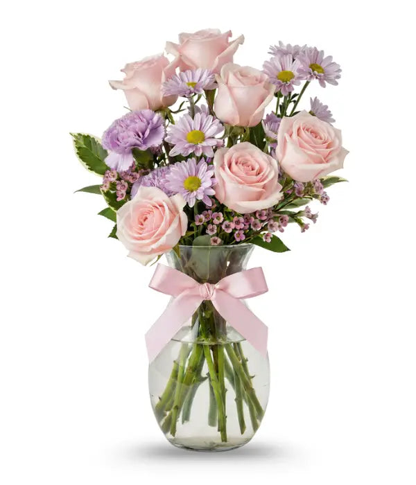 Pink bouquet of roses, daisies, waxflower, carnations and pittosporum in a vase with a pink bow on it