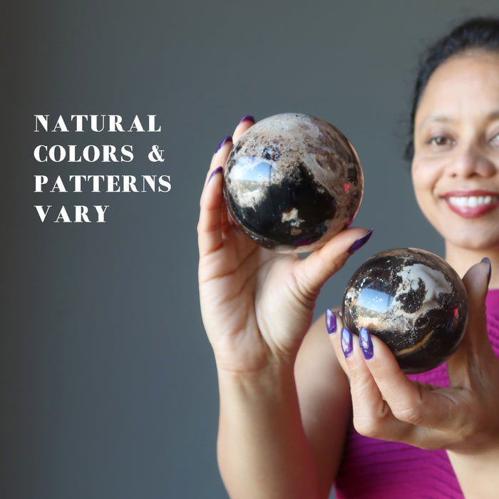 female model holding two brown opal spheres showing natural colors and patterns vary