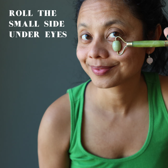female using a green jade facial roller under her eye